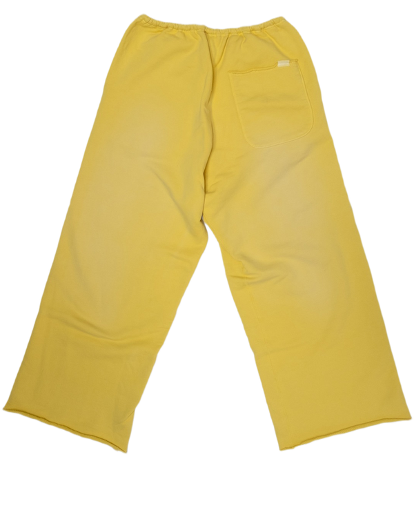 A pair of yellow wide-leg trouser sweatpants shown from the back, featuring an elastic waistband, a back pocket, and a small white brand tag, laid flat on a white background.